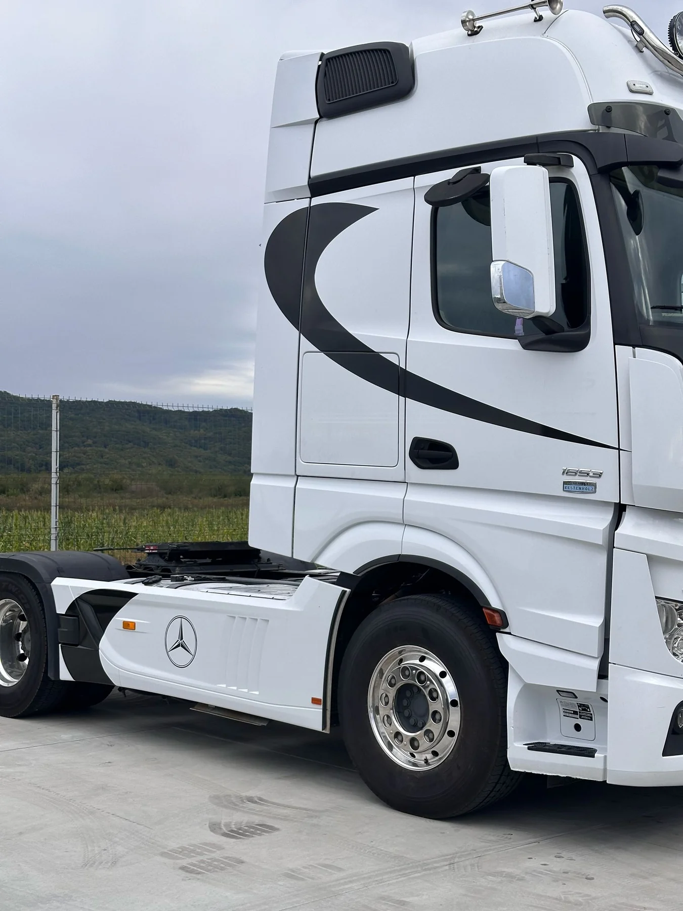 Grafică decorativă neagră pe cabina albă a unui camion Mercedes, partea dreaptă