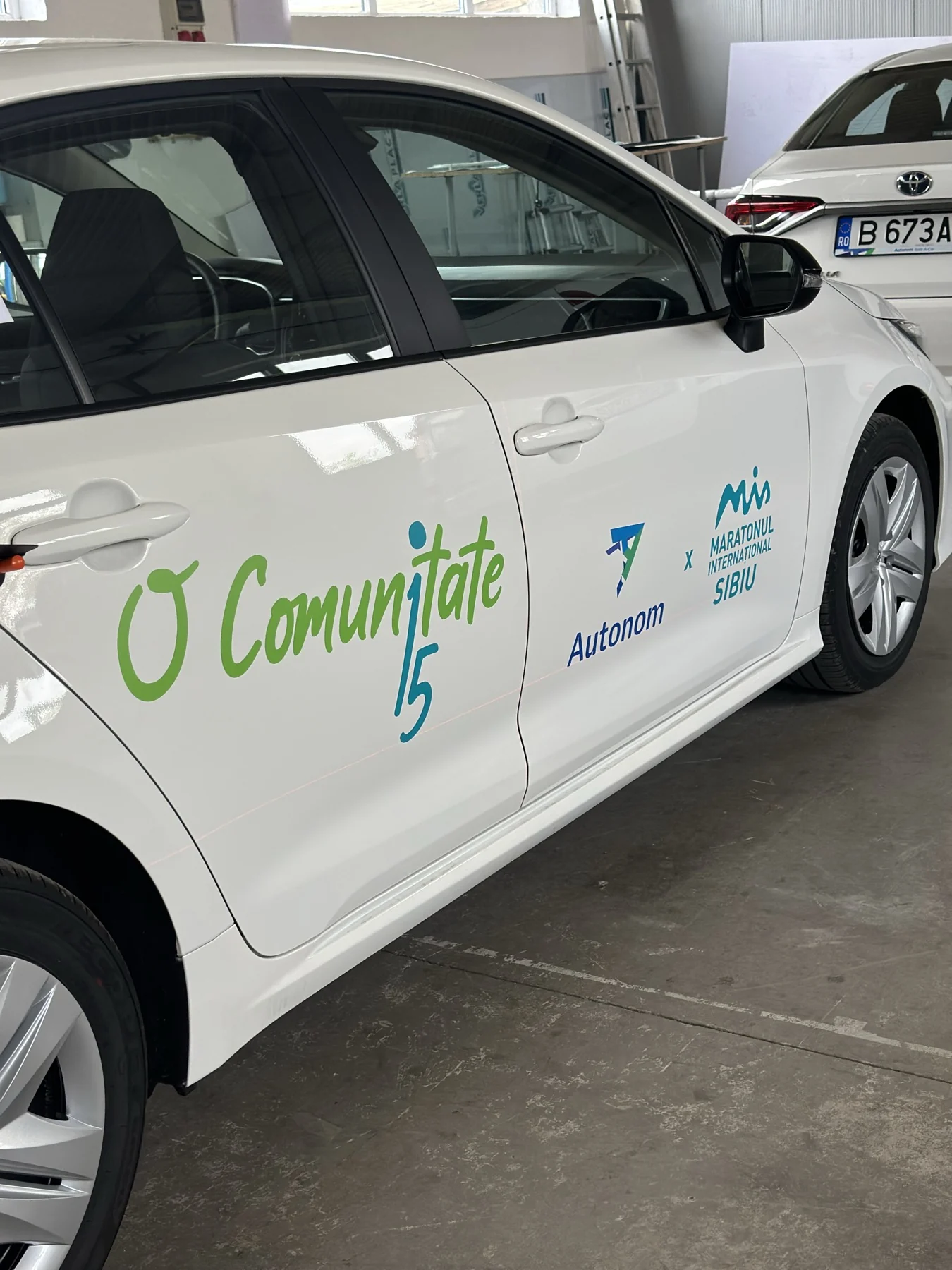 Inscripționare Autonom și Maratonul Internațional Sibiu pe ușile unui autoturism alb